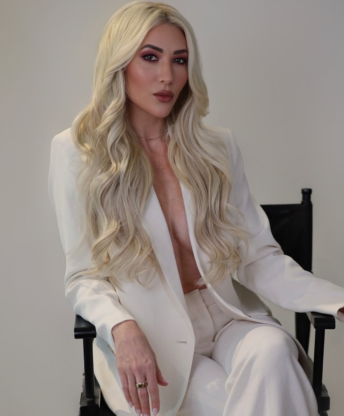 Person in a stylish white suit, seated confidently.