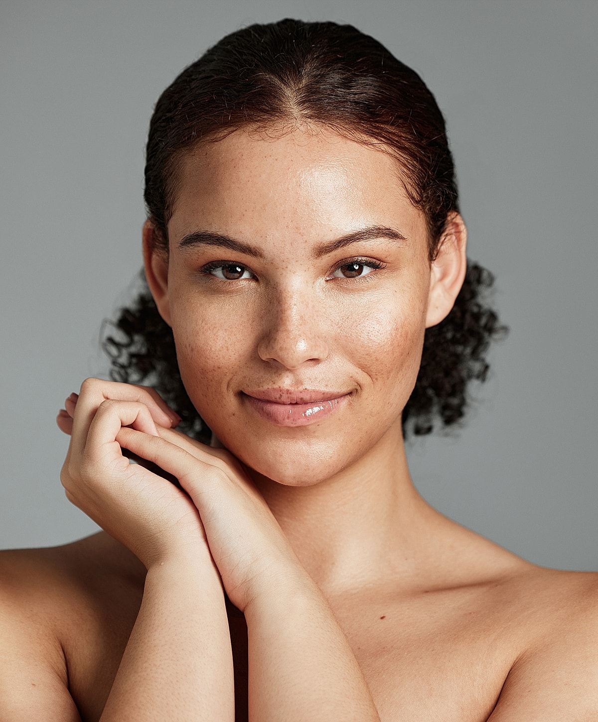 Smiling with hands gently clasped. Natural beauty.