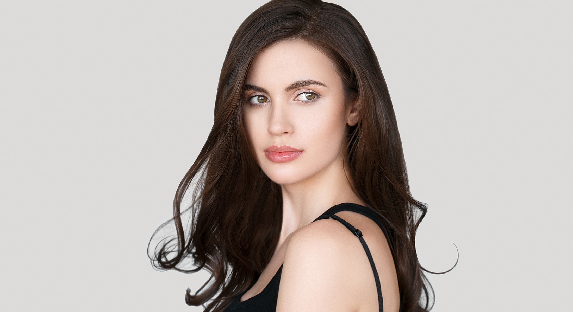 Model with long hair against gray background.